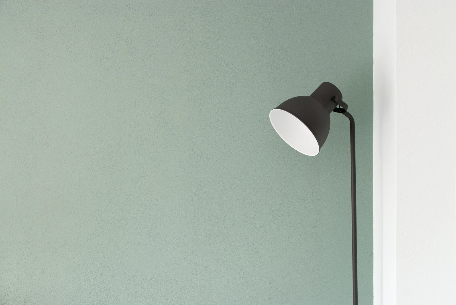 A black task lamp against a pale green studio wall